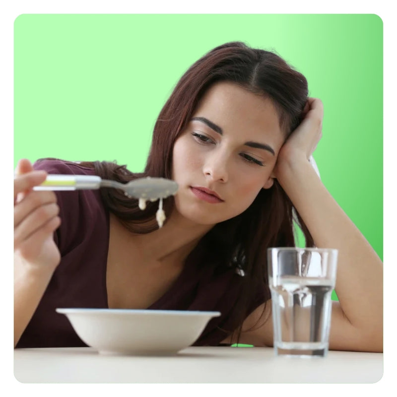 Woman looking unhappily at a spoonful of food, illustrating poor appetite control or diet fatigue.